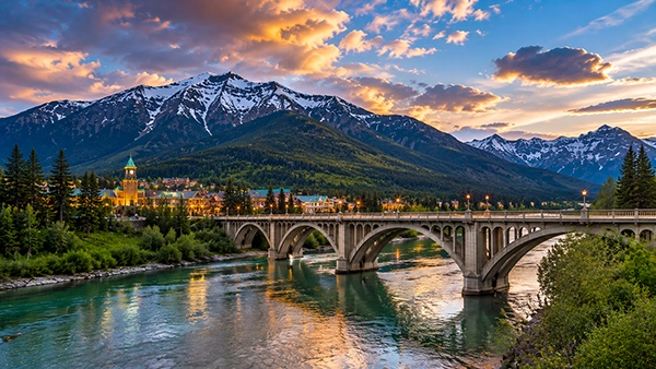 Mountain town at dusk beneath snowy peaks